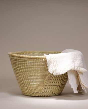Cette corbeille en paille naturelle s'inspire des nasses à poissons. Elle est confectionnée par le peuple du Lesotho, en Afrique du Sud. Cette corbeille est l'accessoire parfait pour organiser vos objets du quotidien. Avec son fond plat et sa forme évasée, elle devient une corbeille très pratique, idéale pour ranger des plaids, des journaux, des jouets, et bien plus encore. L'artisanat traditionnel le plus répandu au Lesotho est celui réalisé à partir d'herbes. Grâce à l'abondance de diverses herbes dans les hautes terres montagneuses, les artisans disposent toujours de matières premières. Les femmes basotho, à travers le pays, démontrent un grand talent dans l'art du tissage de paniers. Ces paniers, fabriqués à partir de robustes herbes locales, sont soigneusement enroulés et maintenus par de fines cordelettes de coton. Matériau – Palme Dimensions approx. : Ø 48 cm x H 27 cm